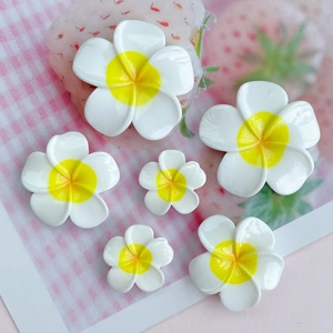 Detailed view of assorted sizes white and yellow resin plumeria flowers for DIY crafts