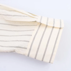 Macro detail of beige striped shirt cuff with neat stitching and a single button