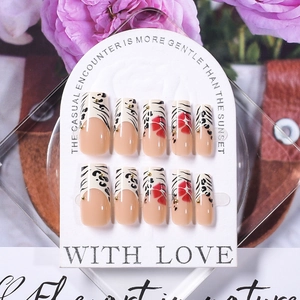 Macro detail of French style ballet nails with leopard print, red flowers and gold beads