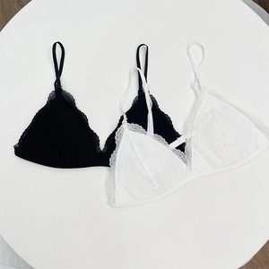 Flat lay of black and white lace triangle bralettes with eyelash trim on a white table