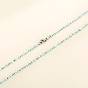 Dettaglio della collana di perline azzurre con maglie argento e chiusura a moschettone