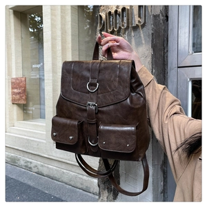 Detailed view of dark brown vintage leather backpack with metallic rivets and buckles