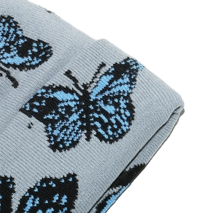 Gros plan détaillé du motif papillon tricoté sur un bonnet d'hiver gris chaud