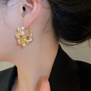 Close-up of elegant floral hoop earrings with pearls and diamonds on a model
