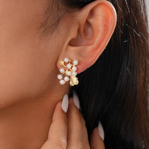 Detailed view of elegant gold pearl flower stud earrings worn on a model's ear