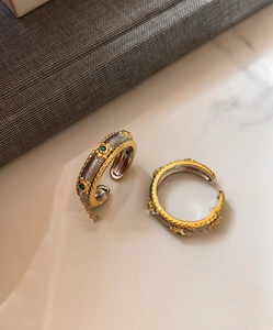 Close-up of vintage textured oval rings with green gemstone details on marble