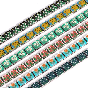 Macro view of modular Italian charms featuring enamel floral designs on stainless steel links