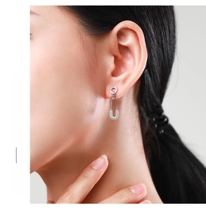 Detail of silver safety pin earrings with cubic zirconia worn by a model