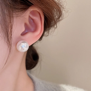Elegant close-up of a model wearing a classic white round pearl earring for women