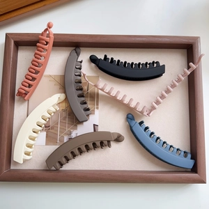 Close-up of assorted matte banana hair clips in multiple colors on a wooden tray