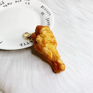 Macro shot of realistic fried chicken wing keychain with golden metal clasp and texture