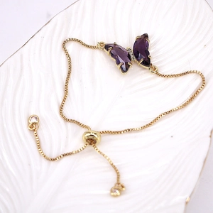 Detail of adjustable gold box chain with a purple crystal butterfly charm on white tray