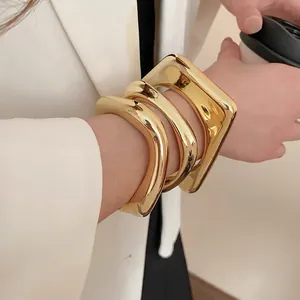 Three-piece gold irregular geometric bangle set with thick square and wavy cuff designs