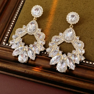 Détail de boucles d'oreilles géométriques dorées avec cristaux sur velours vert