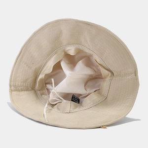 Detail view of the breathable lining and adjustable drawstring inside the beige bucket hat