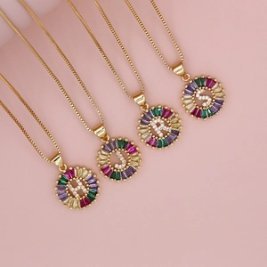 Close-up of gold letter pendants H J R S with colorful zircon stones on box chains