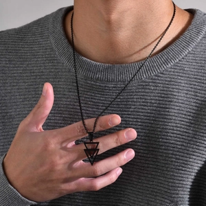 Macro detail of men's interlocking triangle geometric pendant in black stainless steel finish
