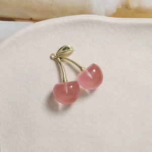 Close-up of pink translucent resin cherry pendant with golden leaf and hanging loop