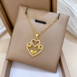 Detail of gold double layered heart necklace with crystals on a beige jewelry cushion