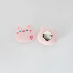 Detail of pink plush cat brooches showing embroidery detail and back safety pin
