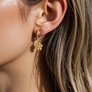 Elegant gold flower drop earrings with sparkling cubic zirconia on a female model
