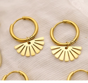 Dettaglio dell'orecchino a cerchio in oro 18K con ciondolo a stella su tessuto