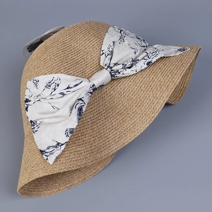 Detail of elegant straw sun hat showing large floral print bow and woven texture