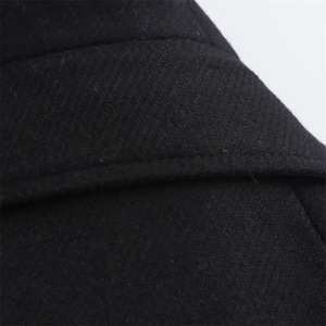 Gros plan sur la texture en laine sergé noir et les détails des coutures du manteau