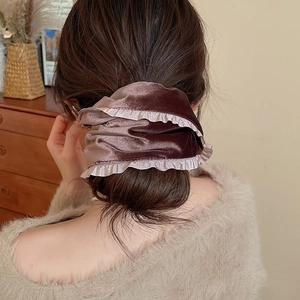 Close-up of elegant dark purple velvet scrunchie with lace trim on a low bun hairstyle
