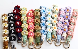 Macro view of twelve colorful handmade woven daisy flower keychains with metal rings