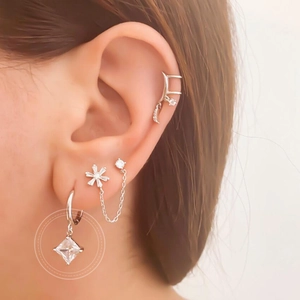 Silver drop earrings set with square zircon pendant and floral stud on earlobe