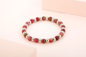 Detail of beaded bracelet featuring textured pink stone and polished silver beads