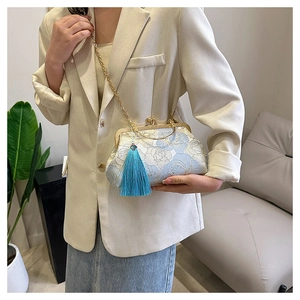Detail of light blue embroidered shell bag with white floral pattern and blue tassel