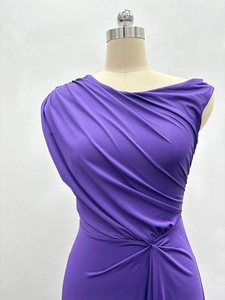 Detail of purple off-shoulder dress featuring ruched waist and glossy textured fabric