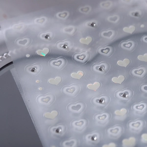 Iridescent heart nail art stickers with small rhinestones on a clear base film