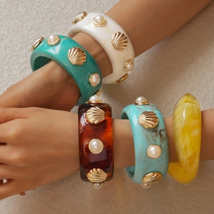 Detail of vintage resin bangles featuring gold shells and faux pearl inlays