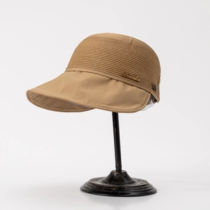 Close-up of woven sun visor with gold metal logo on a dark display stand