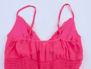 Détail de la robe rose en mousseline avec bustier froncé et volants au décolleté