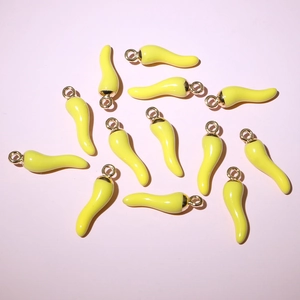 Top-down view of yellow enamel chili charms for DIY jewelry making on a pastel background