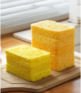 Close-up of porous wood pulp sponges on a wooden board showing natural cleaning texture