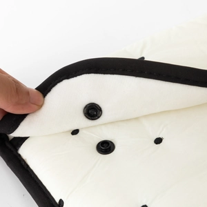 Detail of white quilted tablet sleeve with black dots and a snap button closure