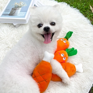 Pomeranian dog playing with plush carrot and drumstick squeaky toys on a soft white rug