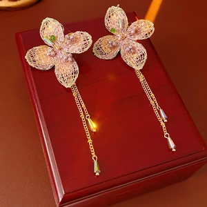 Detailed shot of vintage woven flower earrings with gold chain tassels on a red box