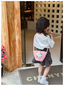 Pink woven crossbody bag for kids featuring a plush sunflower and pearls on a little girl