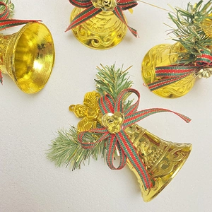 Golden Christmas bell ornament with green pine needles and red plaid ribbon bow