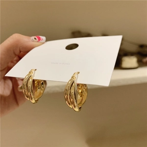 Close-up of golden geometric double-layered cross hoop earrings on white card