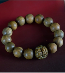 Macro detail of sandalwood beads and lion-shaped carved charm on a classic wood bracelet