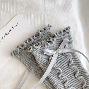 Detail of grey ruffled cuffs and satin bow on Japanese style ribbed knit socks