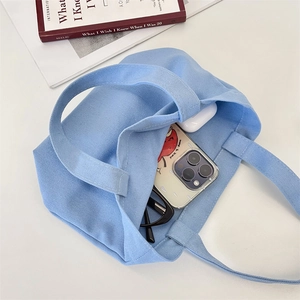 Top view of blue canvas tote showing storage for phone, glasses and earbuds