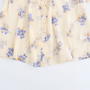 Dettaglio della camicetta in chiffon a fiori blu con bottoni e texture a balze elegante